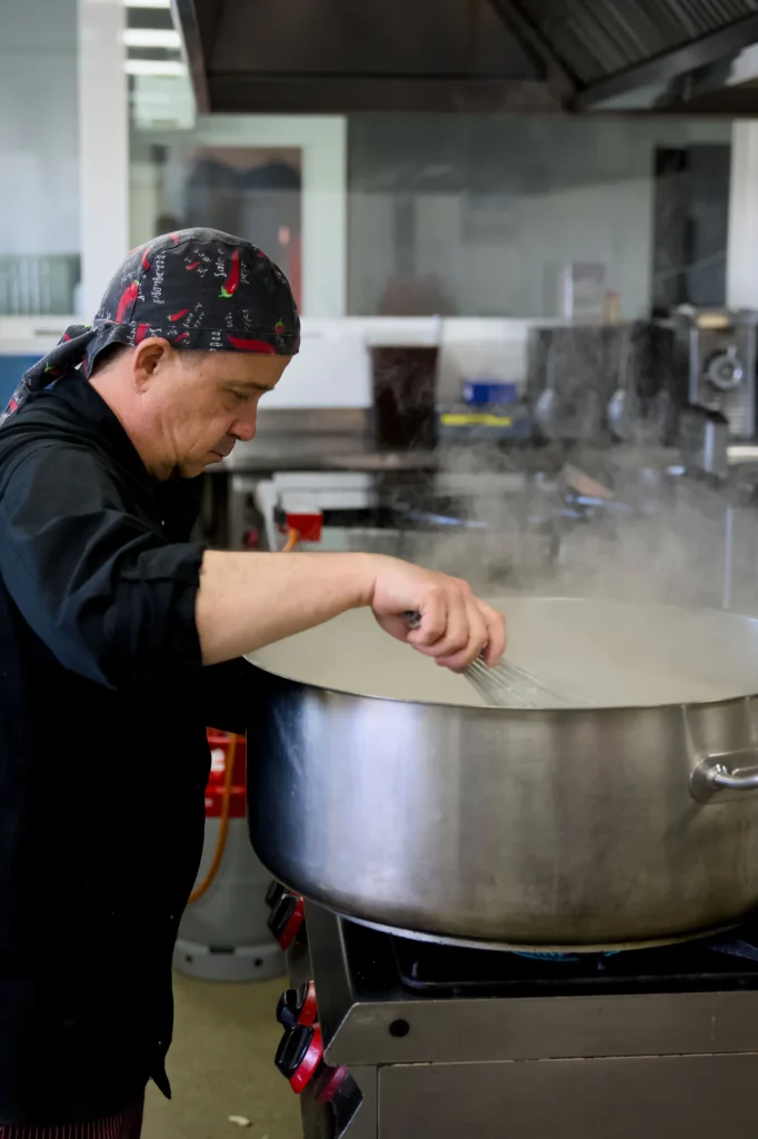 Cocinero preparando un caldo en una gran olla en la cocina propia de La Regenta