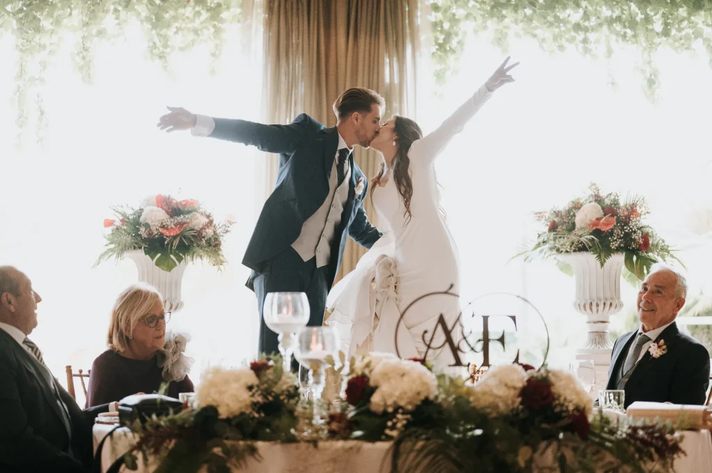 Novios celebrando en la mesa presidencial del banquete de boda