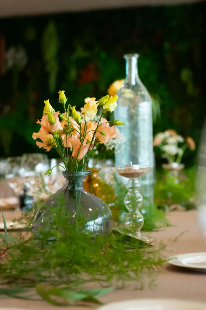 Centro de mesa con flores en tonos melocotón en un jarrón de cristal