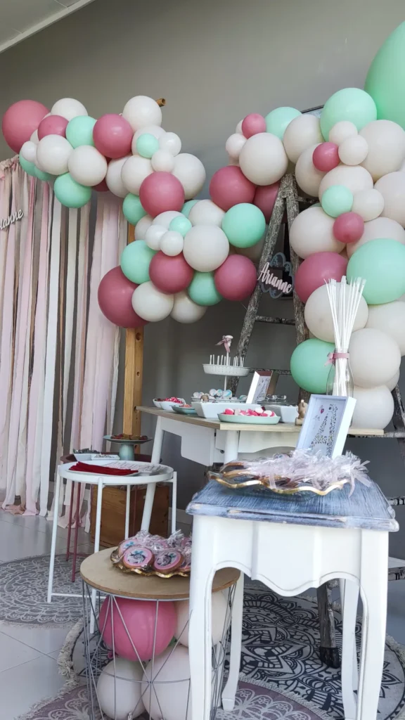 Rincón dulce de comunión decorado con globos en tonos rosa y verde menta