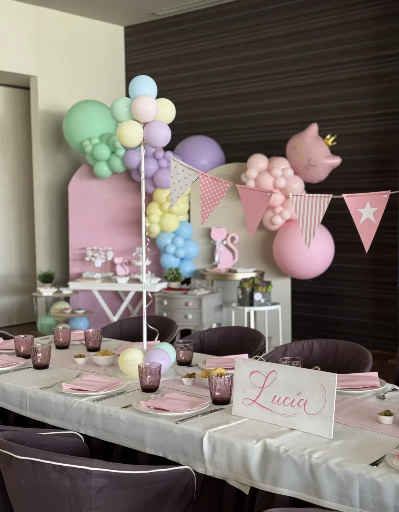 Mesa de comunión decorada en tonos rosa con globos y banderines