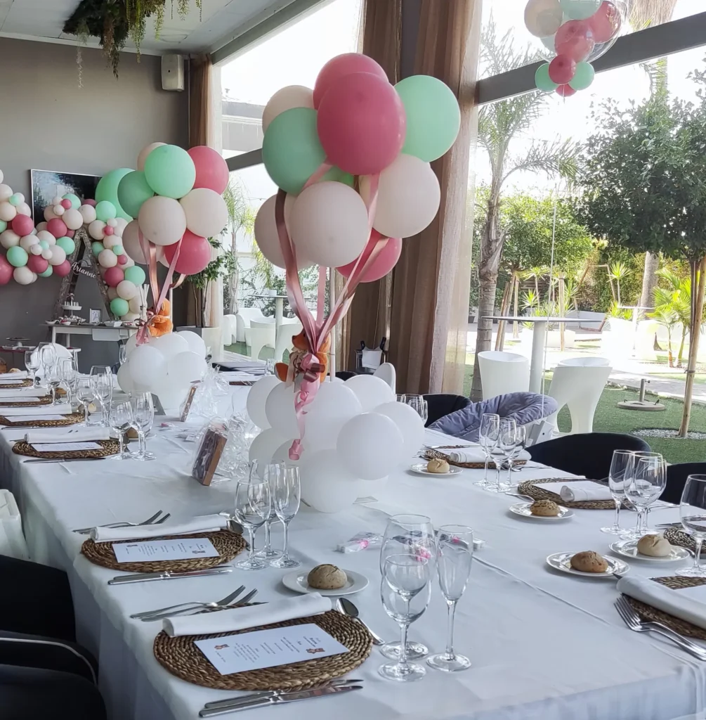 Mesas de comunión con ramos de globos junto a los ventanales del salón