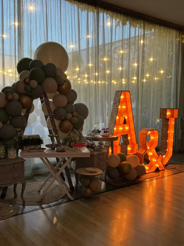 Rincón con iniciales luminosas, guirnalda de globos y luces cálidas en una boda en La Regenta
