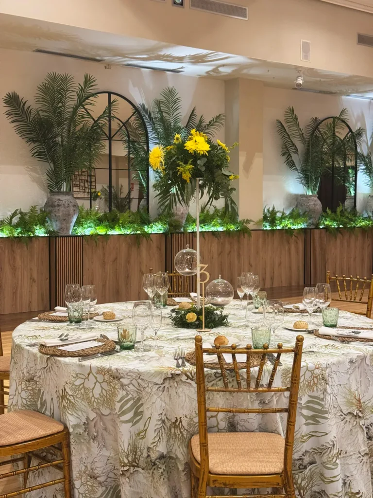 Salón principal de La Regenta, en Castellón, con mesas redondas y jardineras iluminadas