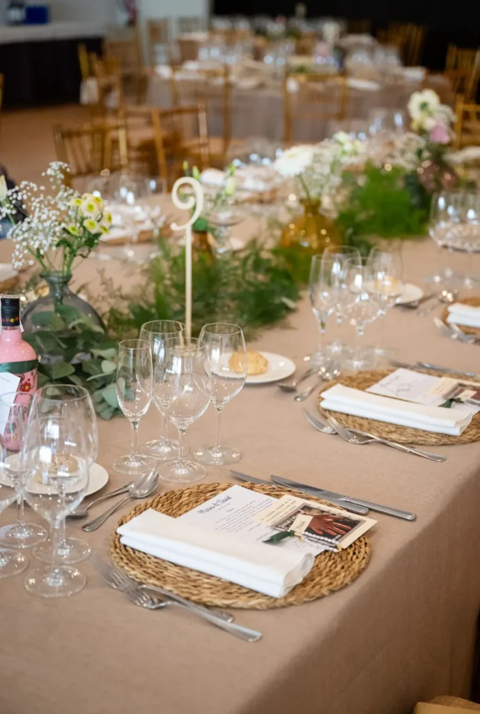 Detalle del montaje de mesa para una boda con bajoplatos de fibra natural y centros verdes
