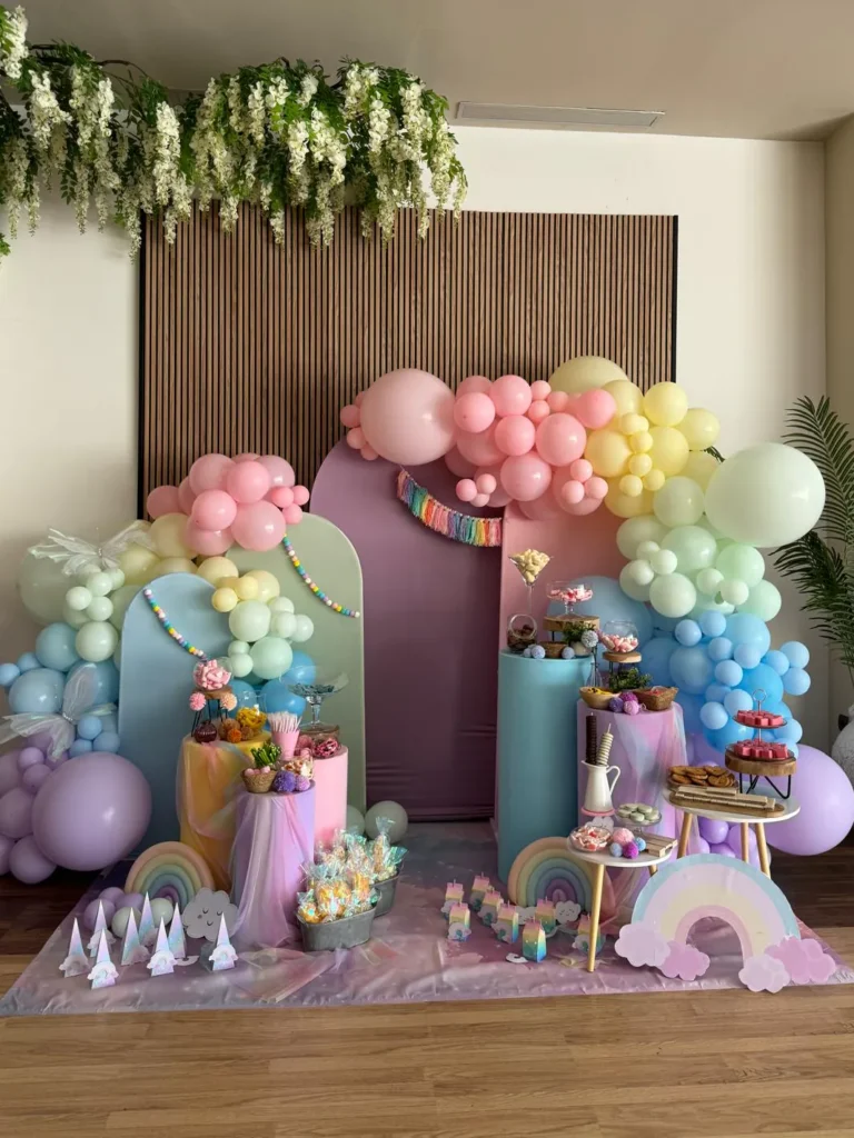 Photocall de comunión con globos en colores pastel y mesa de dulces