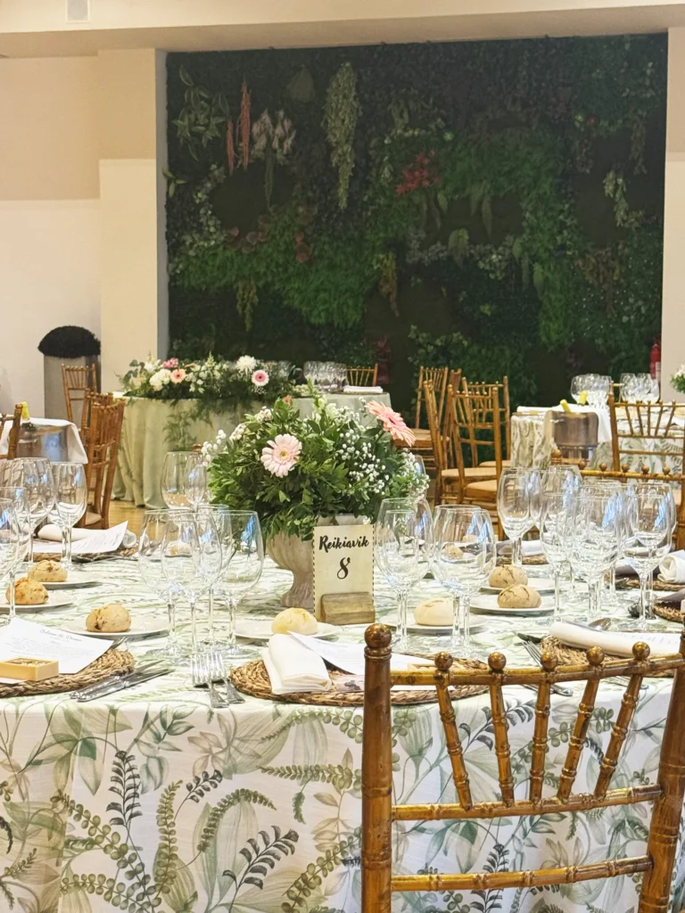 Mesas redondas con mantel de hojas junto a la pared vegetal del salón