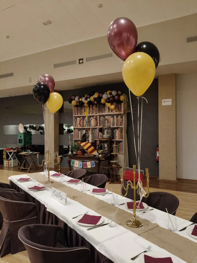Mesa larga de comunión con globos dorados y negros en uno de los salones