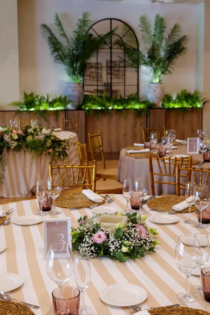 Mesa con mantel de rayas y centro de flores rosas en el salón de La Regenta