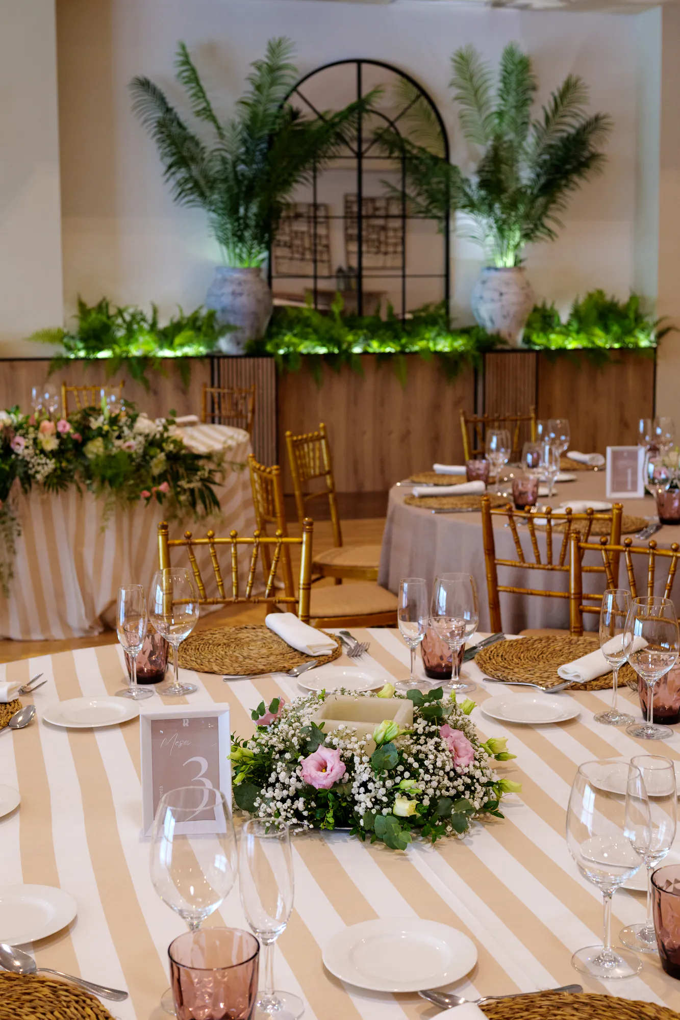 Mesa con mantel de rayas y centro de flores rosas en el salón de La Regenta