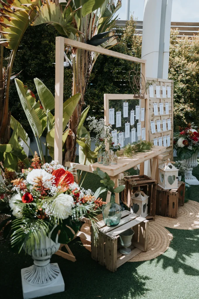 Seating plan de boda con arreglo de flores y plantas tropicales en el exterior